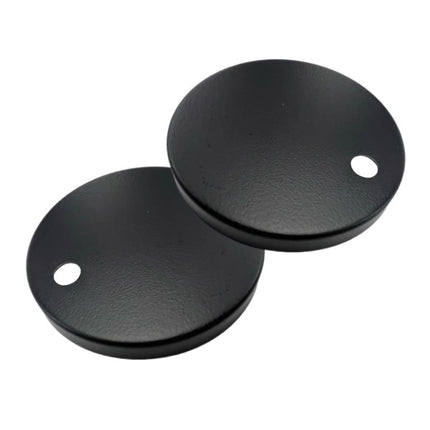 Two black round metal objects with holes on a white background