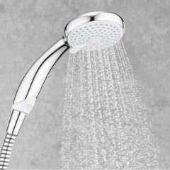 Chrome shower head with water spraying against a gray background